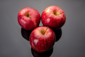 Fresh red apples placed on reflective surface