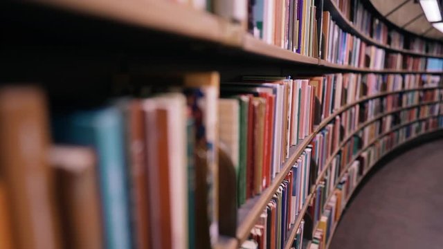 Stedicam shot. Camera moves forward along shelves filled with paper books. The huge round library in Stockholm, Sweden