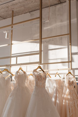 a lot of beautiful white wedding dresses on hangers in the store