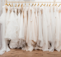 a lot of beautiful white wedding dresses on hangers in the store