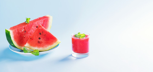 Summer drink, watermelon smoothie in a glass with fresh watermelon slices on a plate on a pastel blue background, summer healthy fruits drink