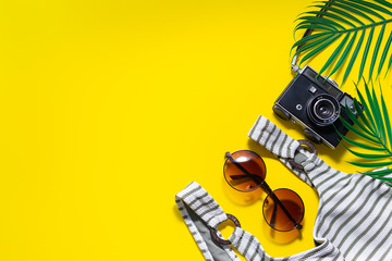 Flat lay overhead of vintage style beach accessories on trendy yellow background with copy space...