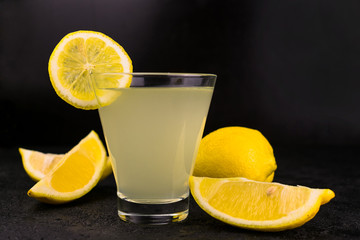Glass with lemon juice on a black background.