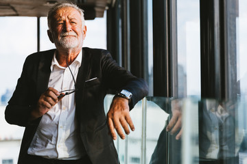 Retirement concept. Senior grey-haired businessman standing and looking to right hand at modern...
