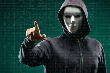 Anonymous computer hacker over abstract digital background. Obscured dark face in mask and hood. Data thief, internet attack, darknet fraud, dangerous viruses and cyber security.