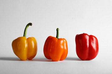 Tricolor peppers standing on white backdrop