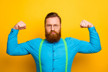 Photo of attractive funny guy seriously raise fists arms presenting perfect shape strong biceps...