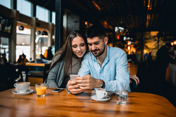 romantic couple in cafeteria drinking coffee and using mobile phone