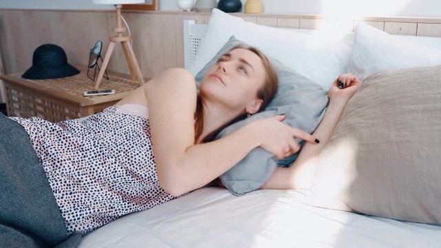 Woman cover head pillow not to hear scream noise neighbors. Cute girl waking in cozy bed on sunny morning. Girl in apartment sleep cozy bed irritated by noise behind wall cannot sleep and nervous