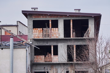An old abandoned concrete unfinished house, with wooden props at Windows. Construction of private...