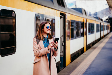 young woman at train station using mobile phone. Travel concept