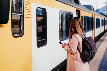 young woman at train station using mobile phone. Travel concept