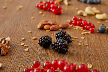 Selective focus of redcurrants, blackberries, cashews, almonds, walnuts on wooden background