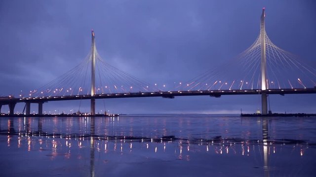 WHSD (Western high-speed diameter) in Saint-Petersburg. Cars ride on new cable-stayed bridge across the Neva river. Rainy weather, the bridge is reflected in wet ice