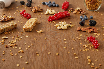 Obraz na płótnie Canvas Redcurrants, blueberries, walnuts, almonds, cashews, oat flakes and cereal bars on wooden background