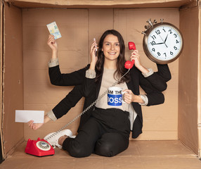 multitasking businesswoman sitting in a cardboard office, doing a lot of things at once
