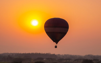 Silhouette of hot air balloon over forest in sunset, sunrise sky background.