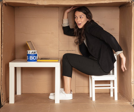young beautiful businesswoman sitting in office cardboard box, tomfoolery around at work