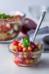 A small bowl of chick pea salad with a large bowl of the same in behind.