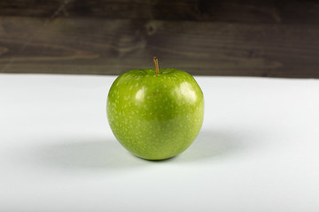 A single green apple on white with lights on it