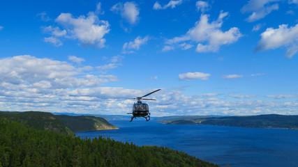 Fototapeta na wymiar Sagenay, Canada - september 2019: Helicopter flying in the Saguenay fjord in one of the most beautiful place in Canada 
