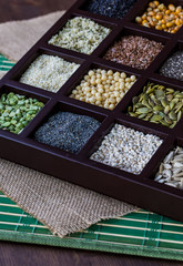 A close up of a wooden box filled with compartments of seeds and grains.