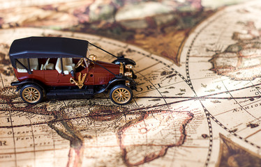 Retro car on the background of a defocused vintage world map, the theme of travel and travel, travel by car and hitchhiking