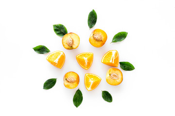 Peach slices and leaves background on white table top-down