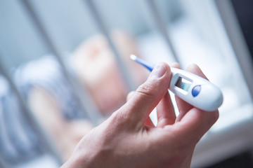 Sick baby at home. Close-up of thermometer