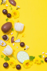 Easter yellow background with chocolatte eggs,    candy and spri