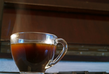 Closeup a cup of hot coffee with smoke on the wooden sideboard