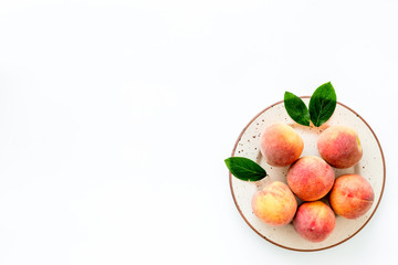 Summer fruits. Ripe red peaches on plate on white table top-down copy space