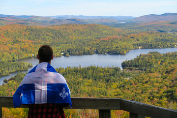 Man wearing the flag of Quebec and admiring the beautiful autumn colours at the Mont-Tremblant...