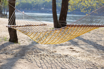 Traditional wattled  hammock with wooden planks hanging between the treas on the sandy beach beautiful sunny aspring (or summer) day