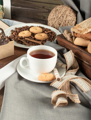 Cookies in rustic trays and a white cup of tea on a rustic table