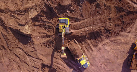 Excavators loading soil onto an Articulated hauler Trucks. Aerial image.