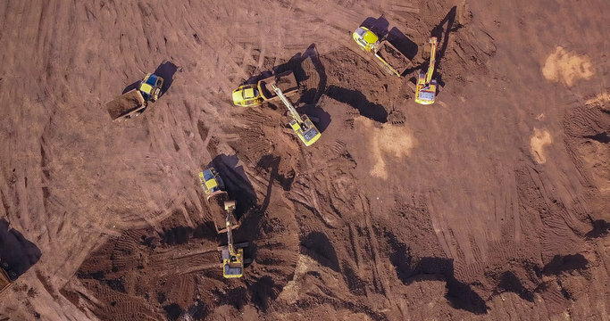Aerial: Vast excavation site with multiple heavy industry vehicles.
