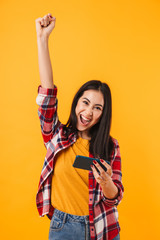 Photo of happy brunette woman using cellphone ad making winner gesture