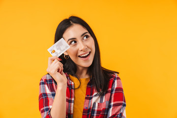Photo of pleased brunette woman smiling while holding credit card