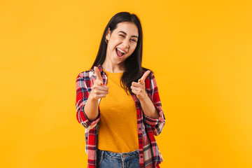Photo of joyful brunette woman winking while pointing fingers at camera