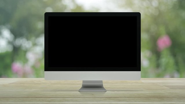 Desktop modern computer monitor with online shopping store graphic and open sign on wooden table over blur pink flower and tree in garden, Business internet shop online concept