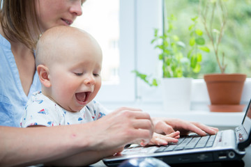 Home office. Mother with cute baby working from home