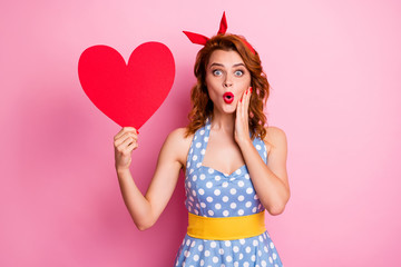 Photo of charming funny lady hold big red paper heart presenting invitation postcard hand on cheekbone open mouth wear headband dotted dress yellow belt isolated pink color background