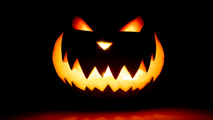 Scary face halloween pumpkin on a black background. Luminous smiling glowing face