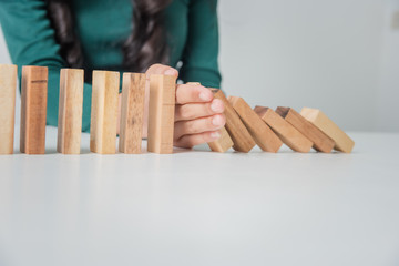 Young woman asian business hand stopping risk the wood blocks from falling, protected asset from risk concept.