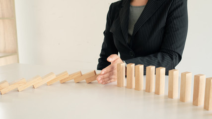 Businessman hand Stopping Falling wooden Blocks, hand stopping falling dominos in a business...