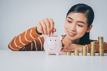 Young asian woman with stack of coins and piggy bank, growing up employee bonus concept.