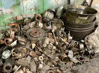 Dump of old auto parts in the garage of an auto mechanic. A bunch of unusable car parts. Garbage from worn auto parts.