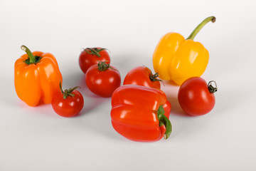 Red tomatoes and peppers on a white background with shadows. top view