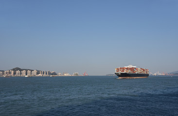 Landscape of sea coast, near Xiamen China, with large container ship departing from the sea port. 
